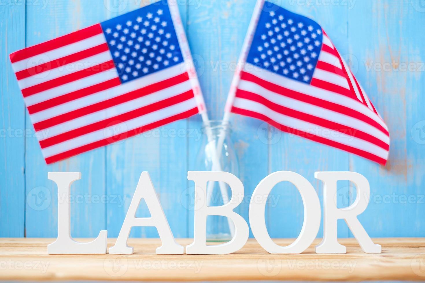 arbeitstext und flagge der vereinigten staaten von amerika auf holztischhintergrund. Happy Labor Day und Feiertagsfeierkonzepte foto