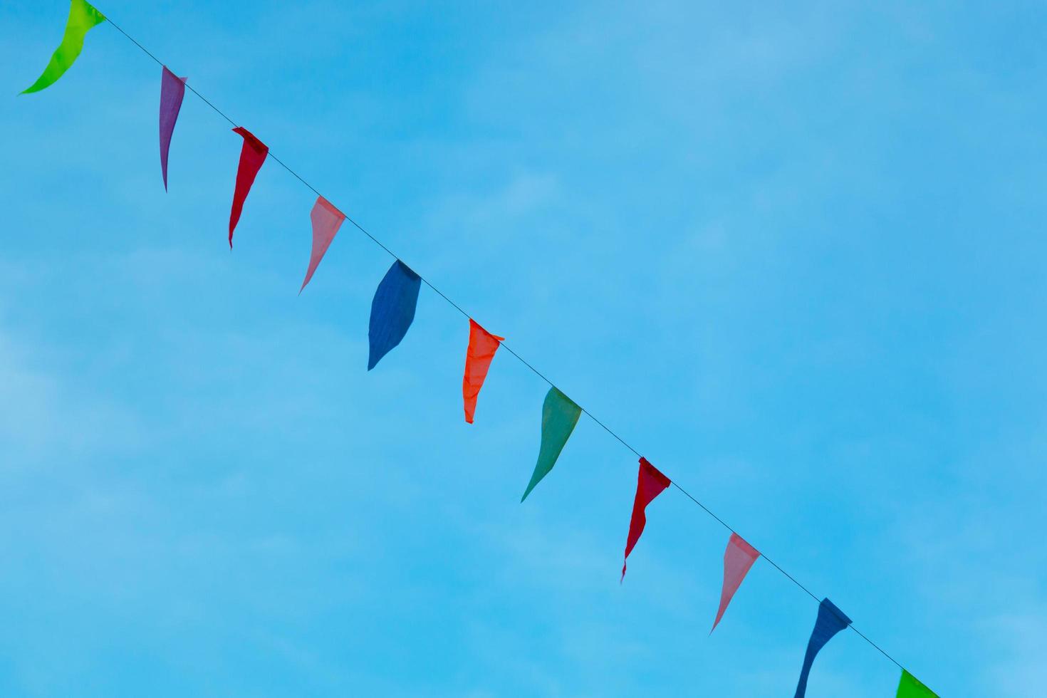 Bunte Wimpel, die mit einem Seil gegen den blauen Himmel hängen. foto