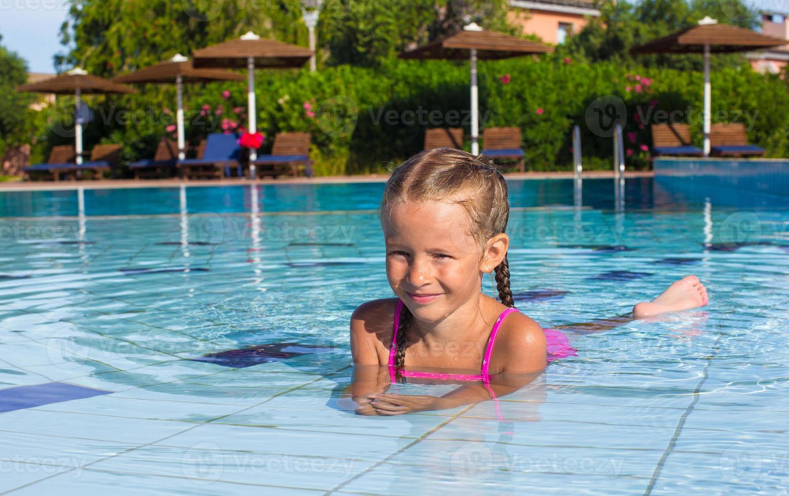 entzückendes glückliches kleines Mädchen genießen, im Pool zu schwimmen foto