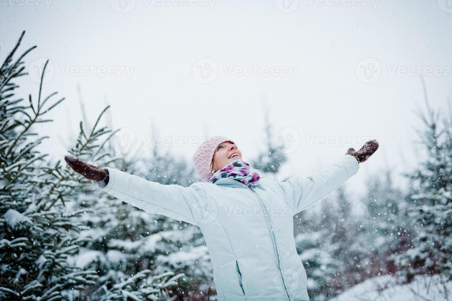 glückliche süße Frau, die Winter während eines verschneiten Tages genießt foto