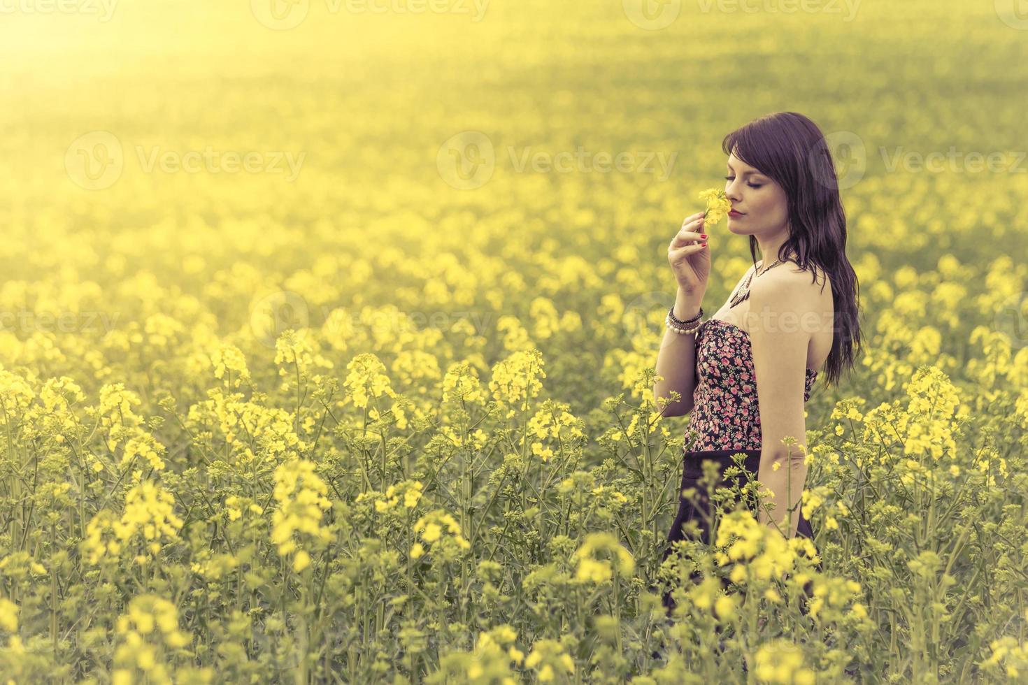 schöne Frau in der Wiese der gelben Blumen, die Blume genießen foto