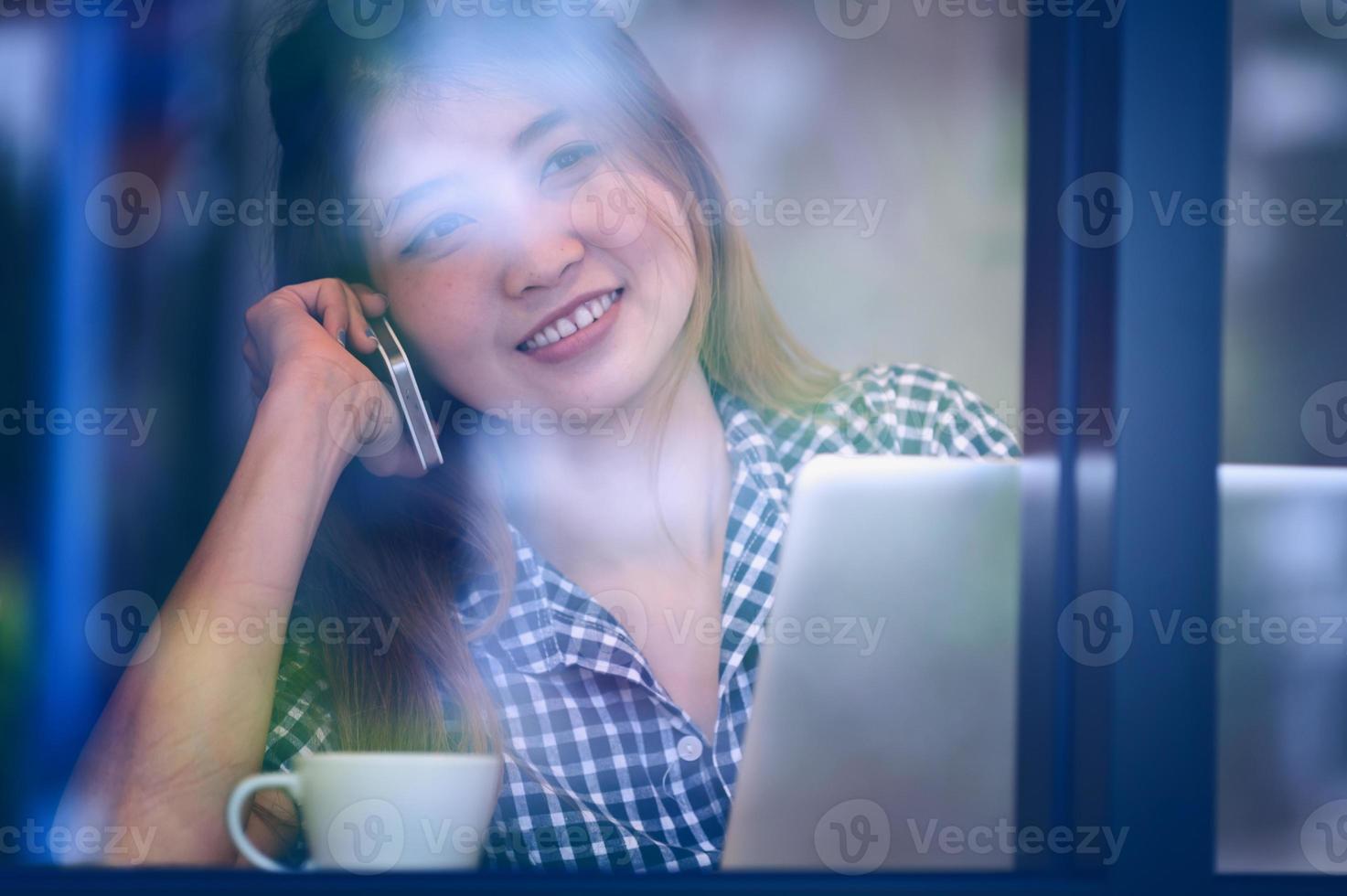 Asien glückliche Frau, die Telefon im Café spricht und Kaffee genießt foto