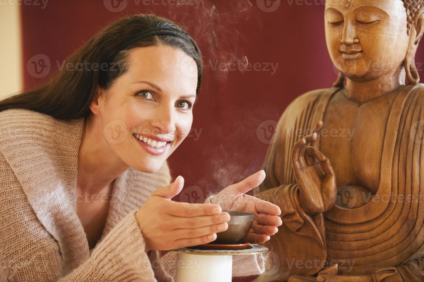Brünette Frau genießt Joss Sticks Duft Buddha Statue im Hintergrund foto