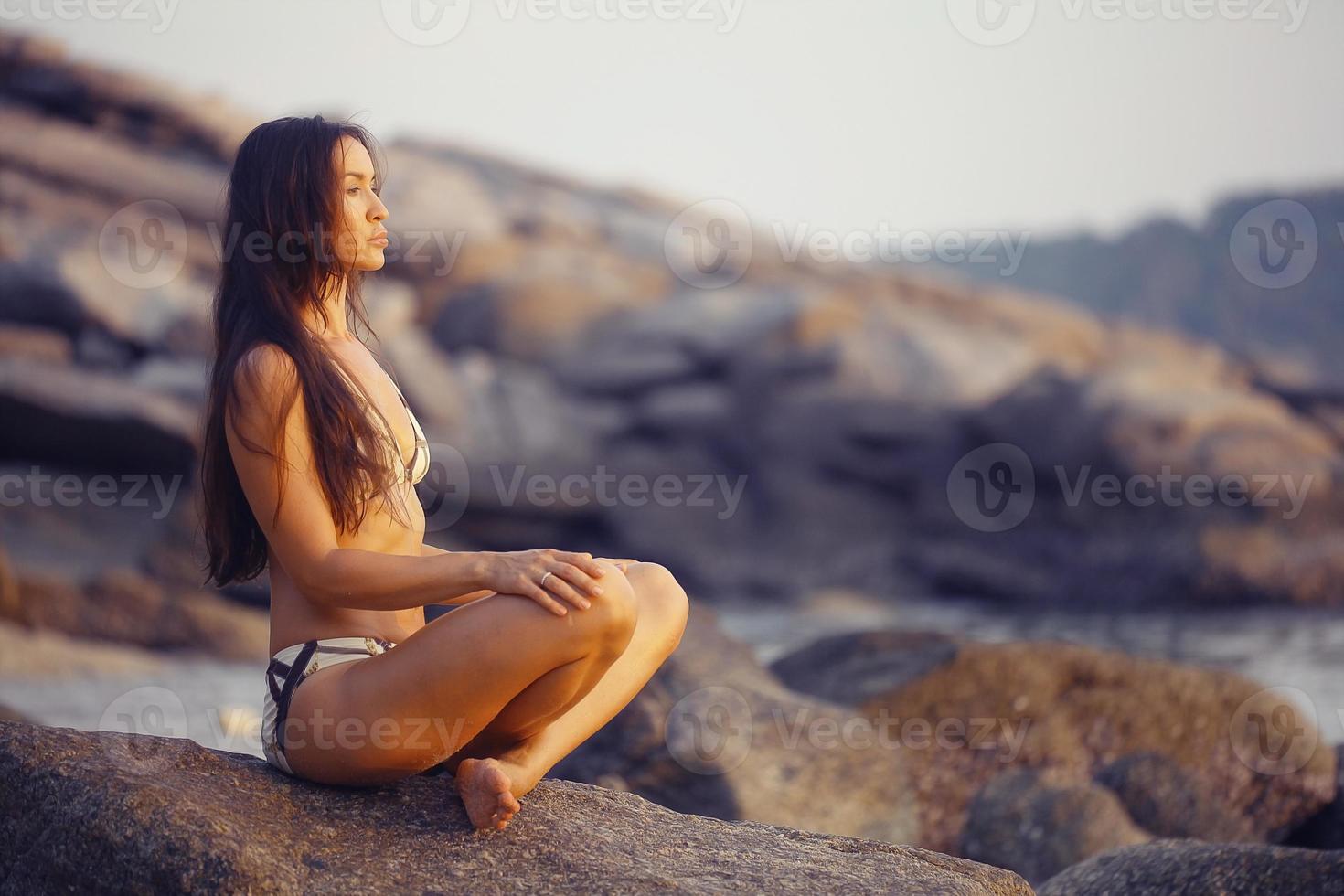 Frau meditiert am Strand der Meeressonne foto
