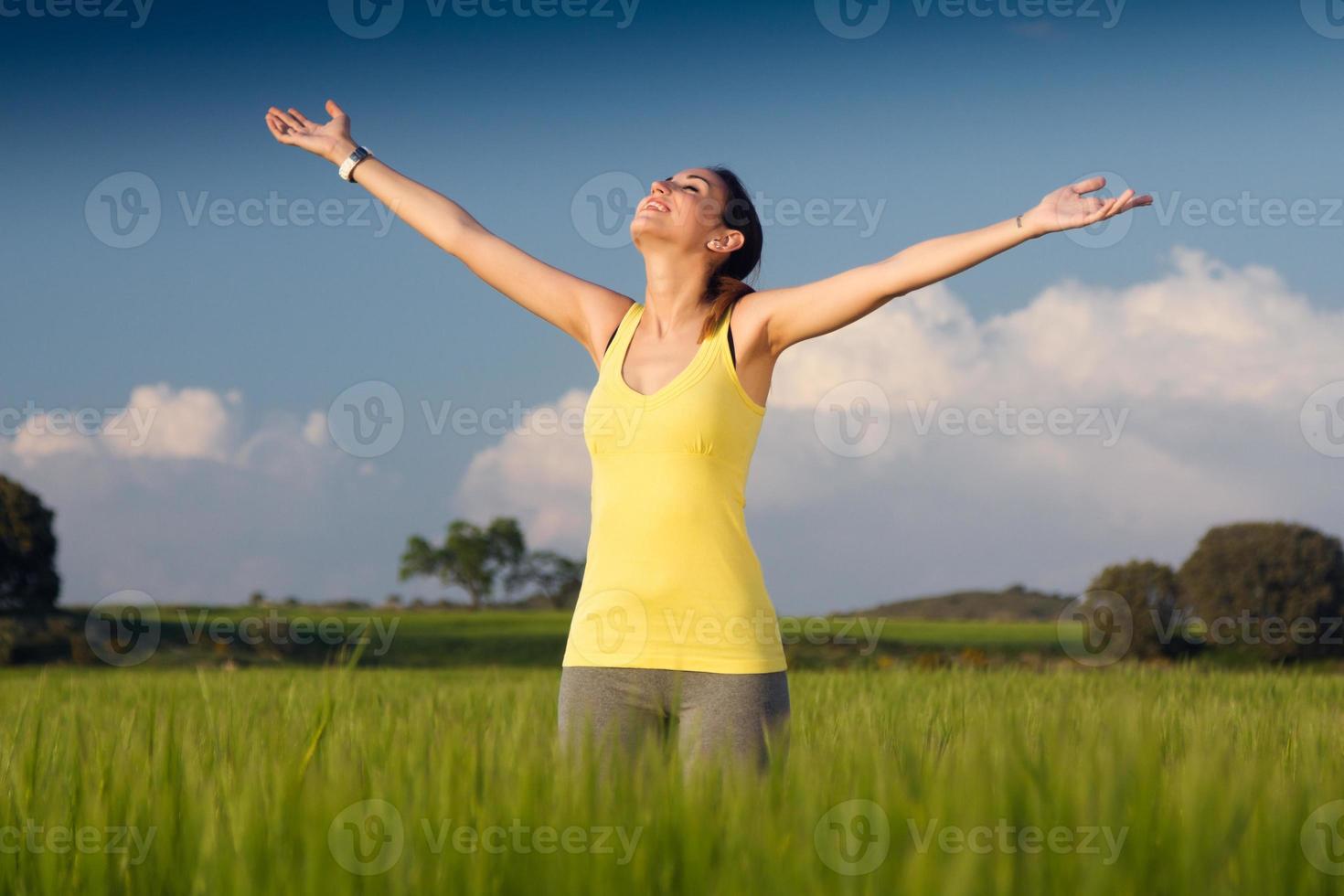 junge Frau, die den Frühling genießt, der in einem Getreidefeld steht foto