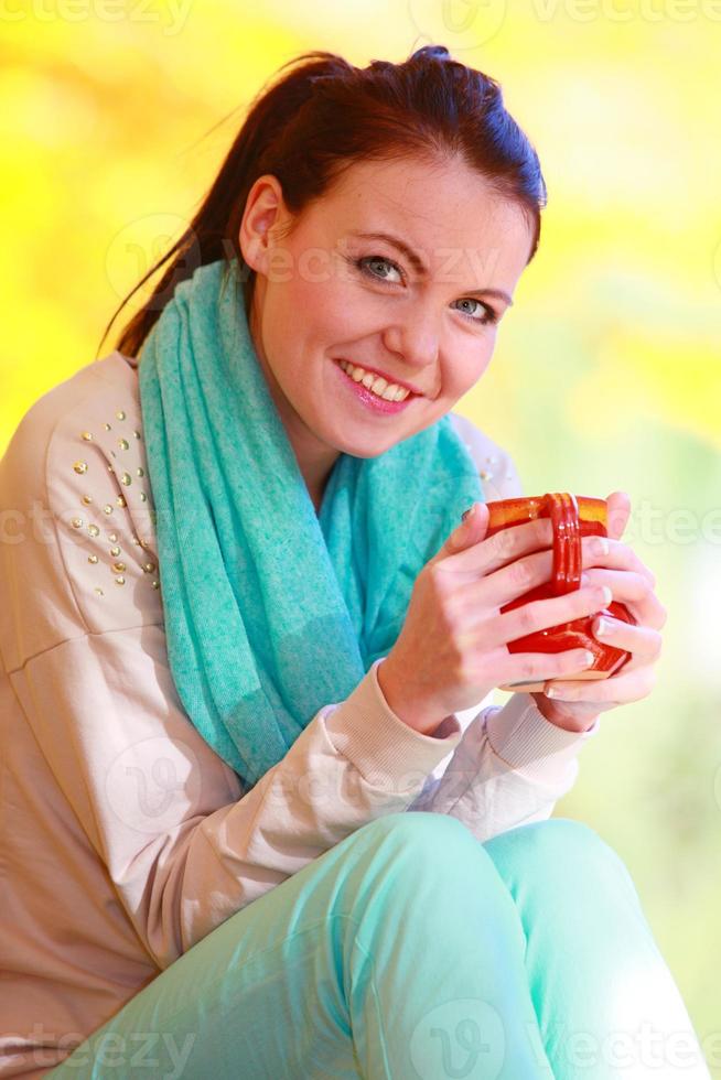glückliches Mädchen, das im Herbstpark entspannt heißes Getränk genießt foto
