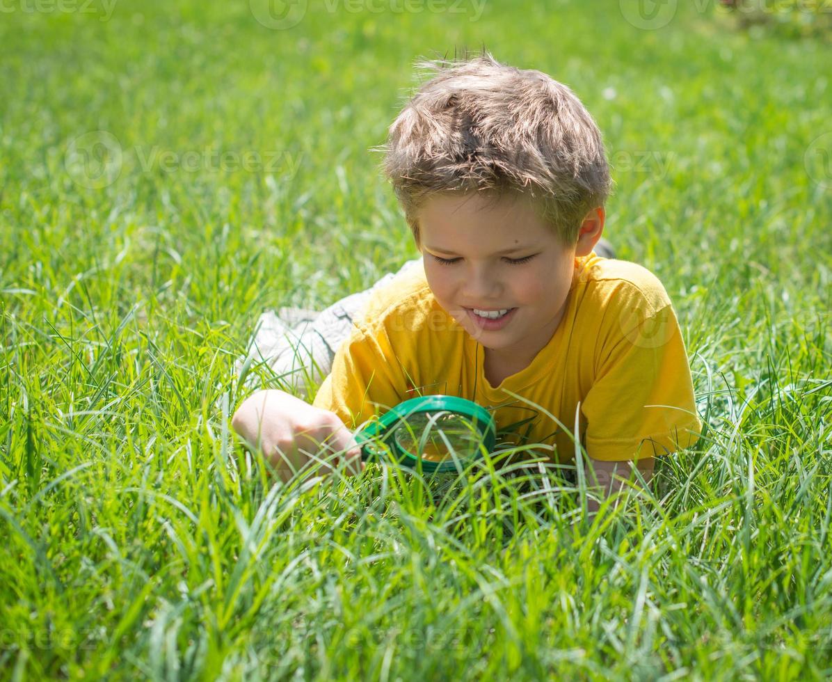 Kind mit Lupe im Freien. glücklicher Junge, der sonnigen Sommer genießt. foto
