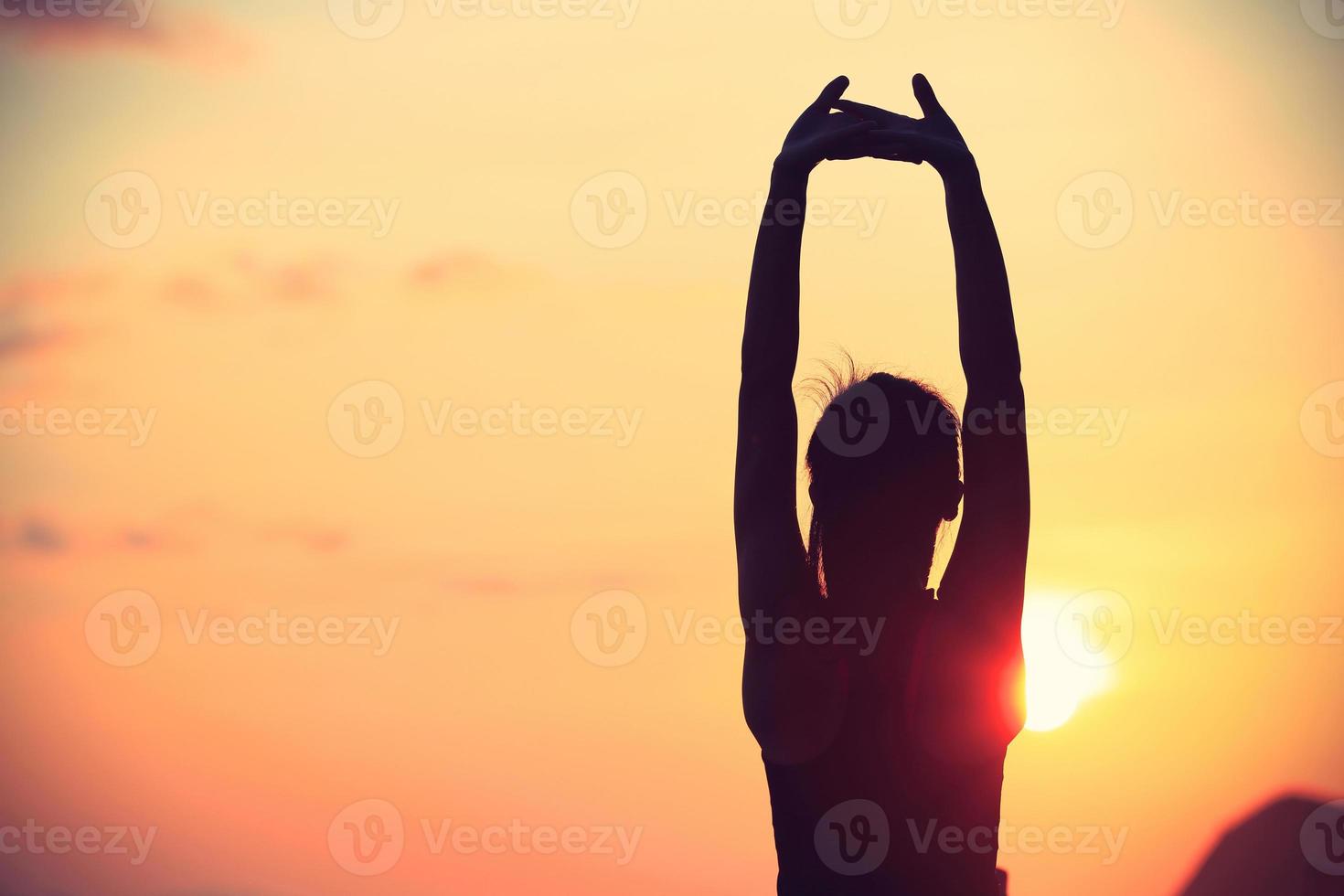 gesunde Fitness Yoga Frau, die Arme am Sonnenaufgang Meer streckt foto
