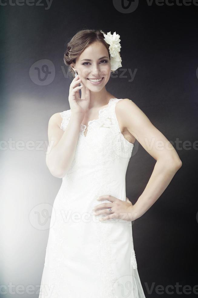 glamouröse junge Braut im Hochzeitskleid, lächelnd foto