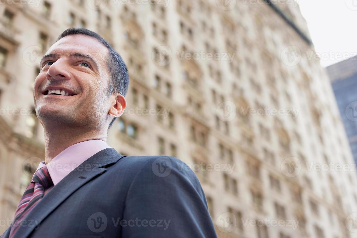 Geschäftsmann, der gegen unscharfes Gebäude lächelt foto