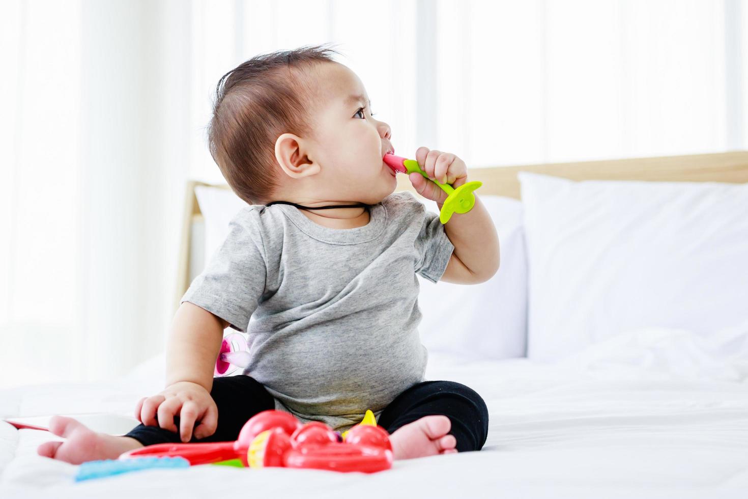 hübsches Baby spielen Babyspielzeug auf dem Bett. 8 Monate glückliches Baby. Entwicklung im Babykonzept. foto
