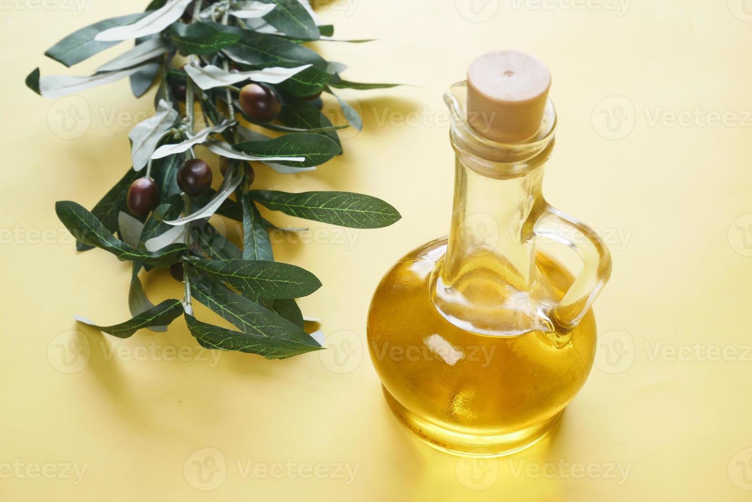 Flasche Olivenöl und frische Oliven in einem Behälter auf dem Tisch. foto