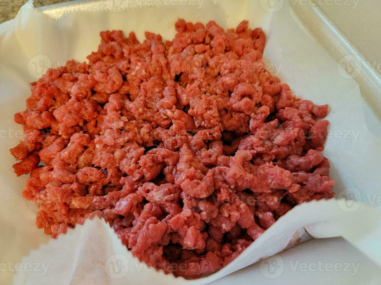 Haufen von gemahlenem rohem rotem Rindfleisch in Schaumbehälter foto