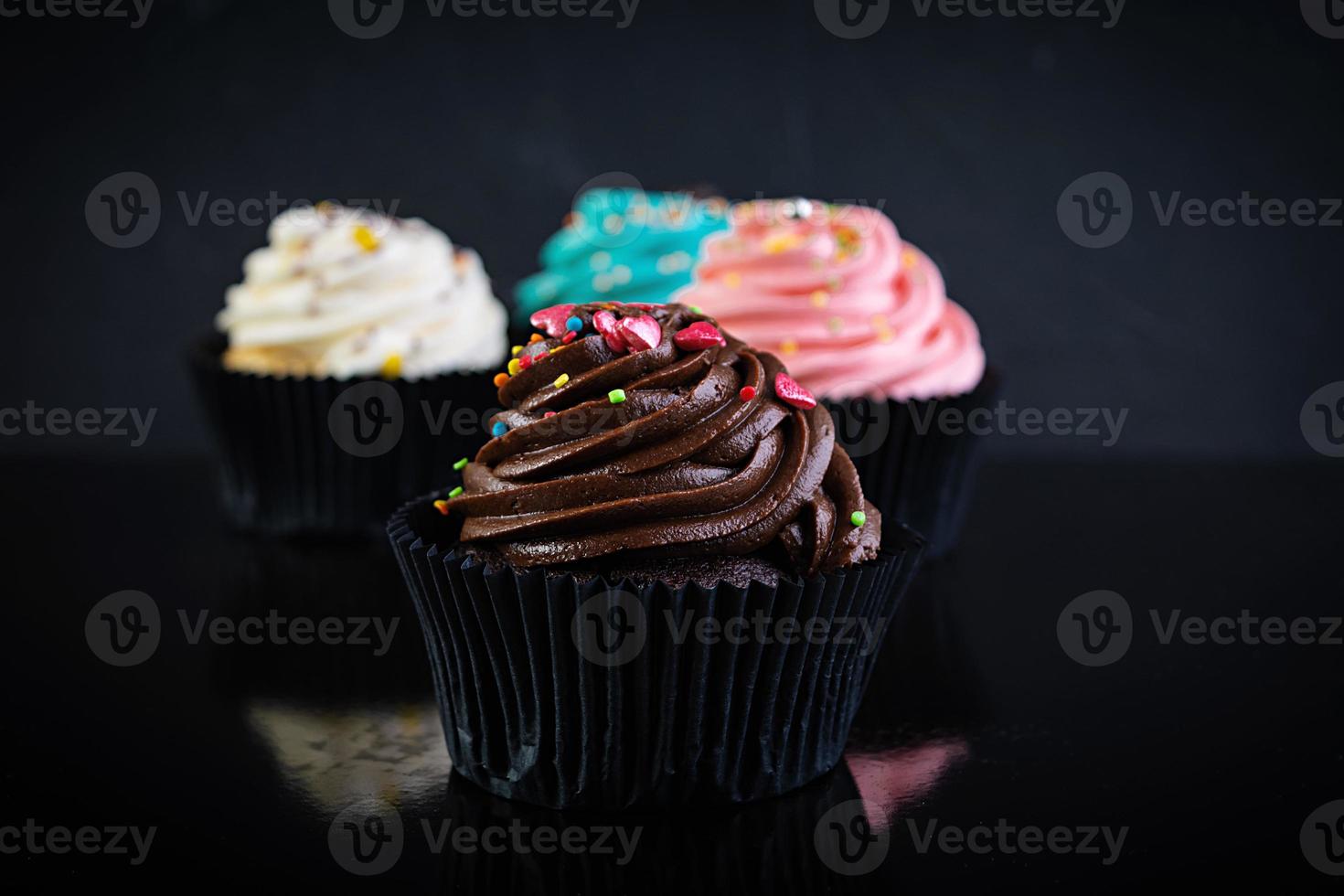 leckere bunte Cupcakes isoliert auf dunklem Hintergrund. leckerer Cupcake foto