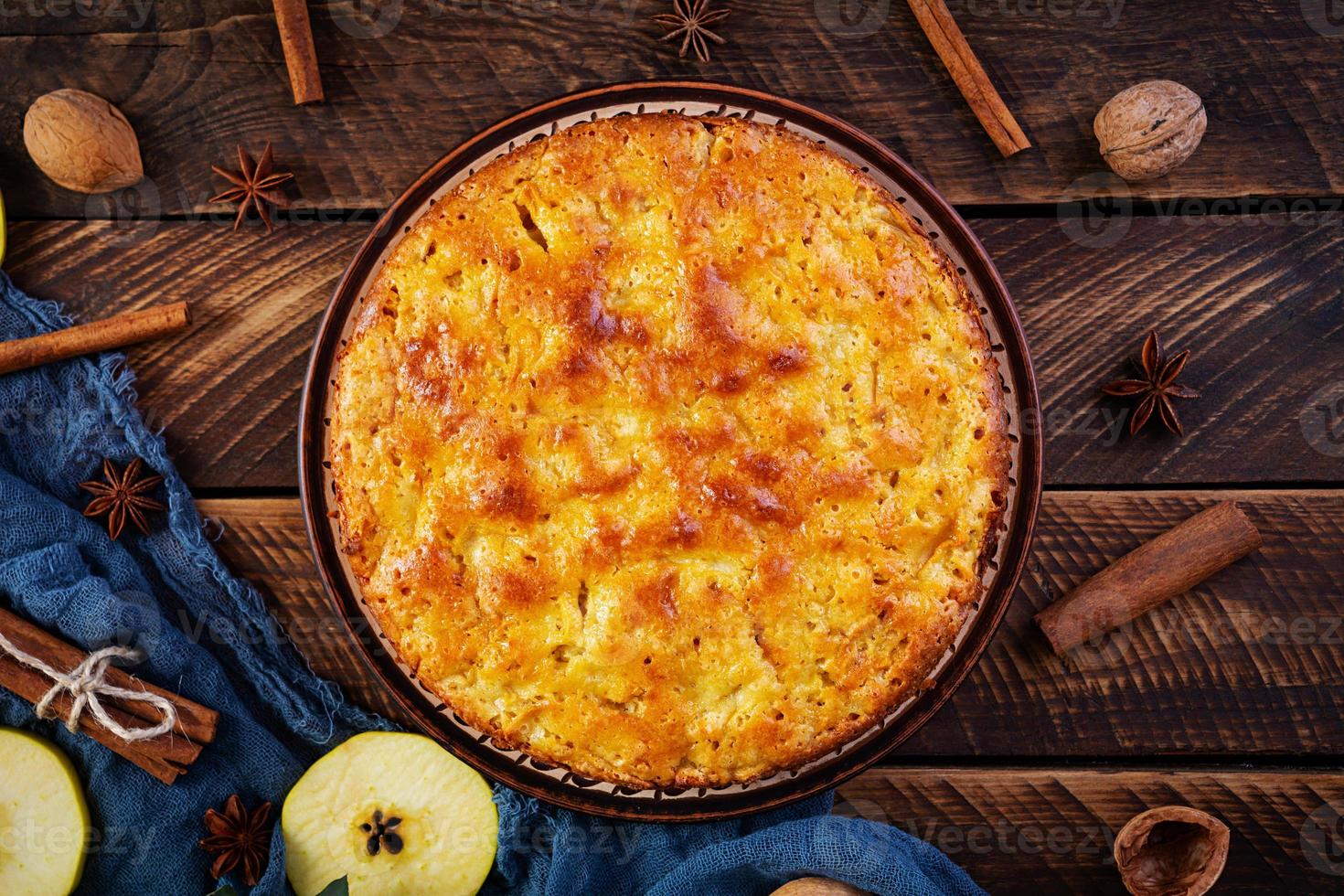 köstlicher hausgemachter Apfelkuchen auf Holzhintergrund. Apfelkuchen mit Zutaten, Äpfeln und Zimt. Ansicht von oben foto