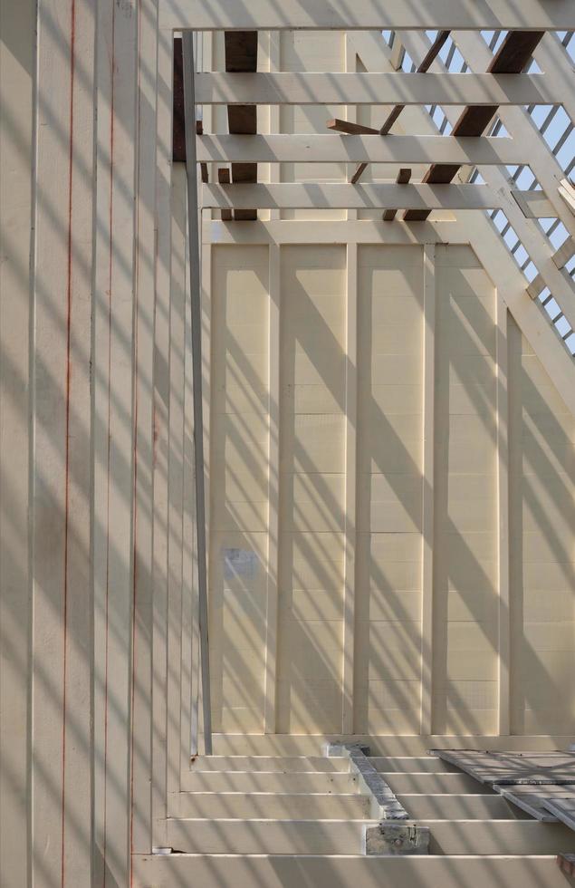 sonnenlicht und schatten auf der oberfläche der weißen holzdachstuhlkonstruktion im bau in vertikalem rahmen, bau- und architekturkonzept foto