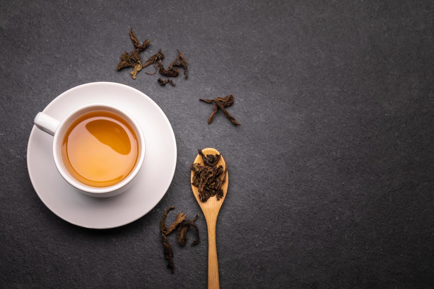 draufsicht tasse tee mit trockenem blatt auf schwarzem stein foto