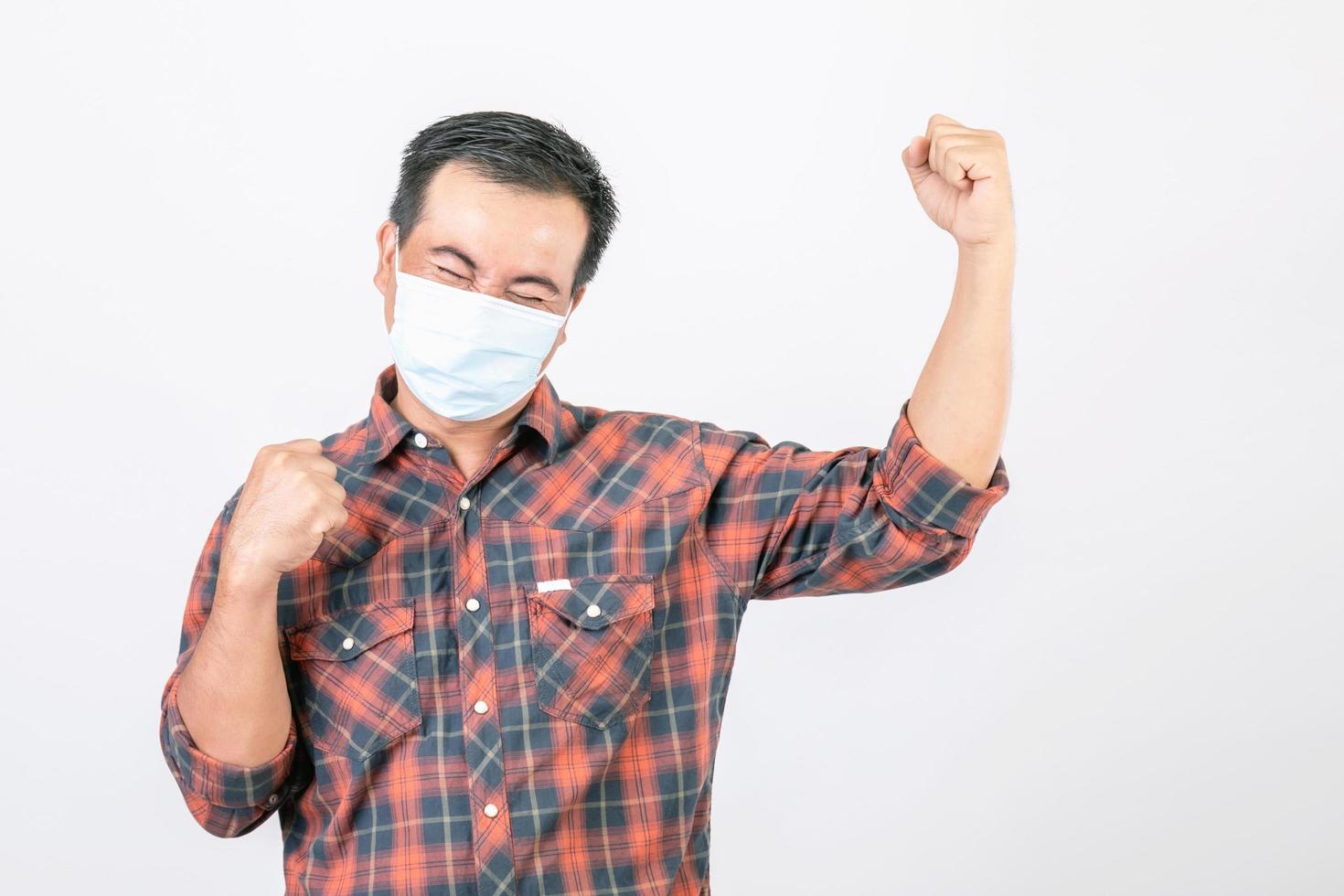 schlechtes Situationskonzept bestanden, asiatischer Mann mit schützender Gesichtsmaske in Aktion von froh, Sieg oder sehr glücklich isoliert auf grau foto