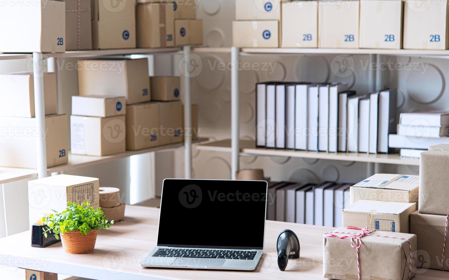 ausrüstungen für kleine und mittlere online-geschäfte, laptops für lieferungsunternehmen, barcode, kartons, produktprüfung auf beständen oder paketen. kleines Unternehmen, das im Home Office arbeitet. foto