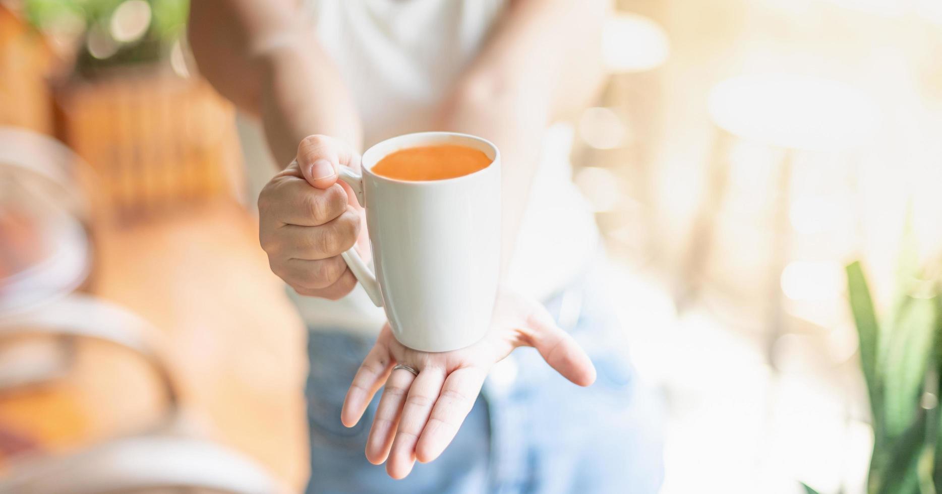 Frauenhand, die eine Tasse mit Tee hält, während sie im Wohnzimmer sitzt und sich entspannt. und Platz kopieren. foto