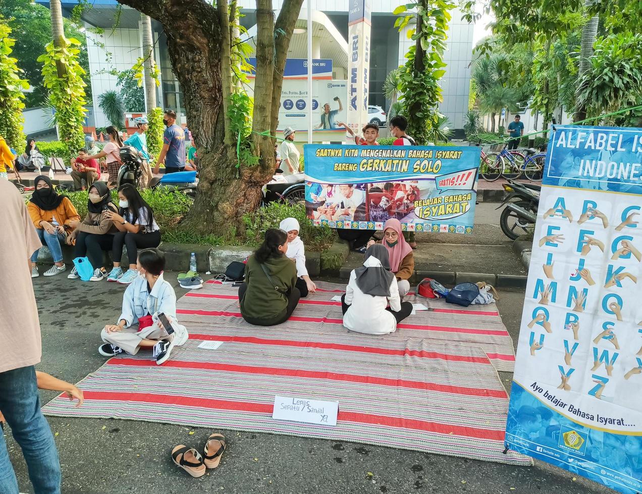 sukoharjo - 7. juni 2022 - menschen mit behinderungen sitzen auf matten und unterrichten fußgänger in gebärdensprache foto