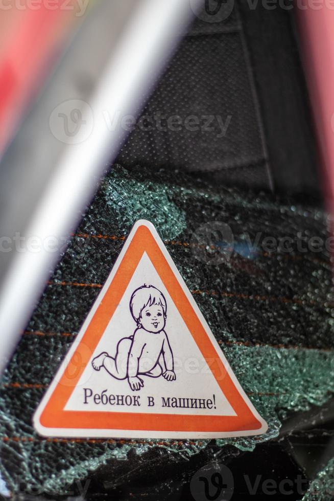 Warnzeichen von Kindern in einem Auto nach einem Unfall mit blutigen Glasscherben. übersetzung kind im auto. Nahaufnahme des weißen Baby-an-Bord-Aufklebers auf der Heckscheibe des Autos. vertikales Foto. foto