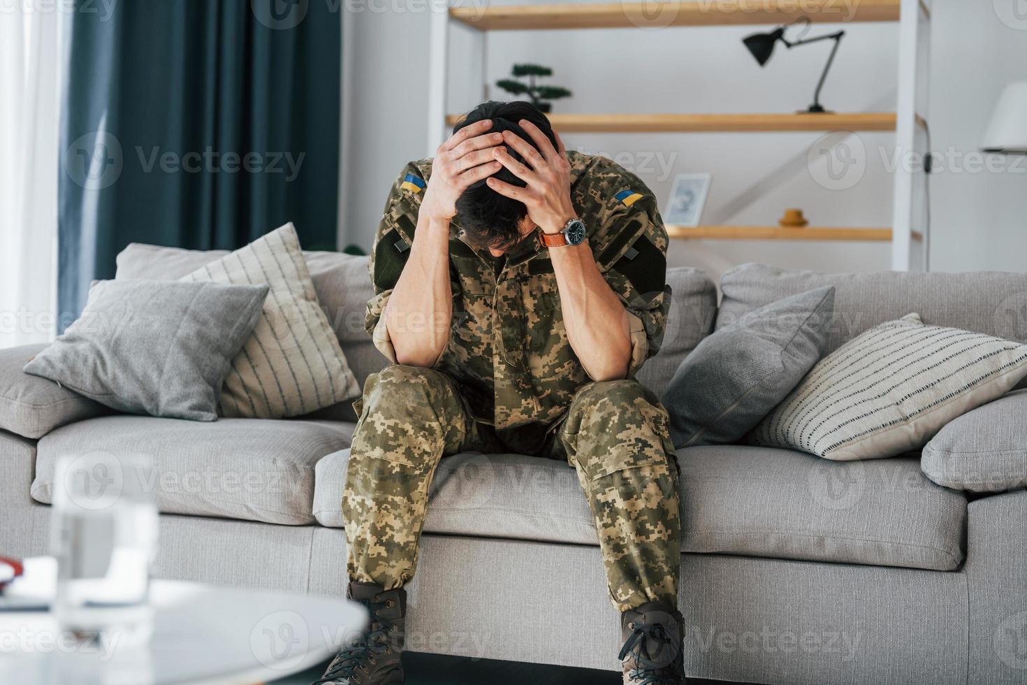 Flashbacks haben. Posttraumatische Belastungsstörung. Soldat in Uniform sitzt drinnen foto