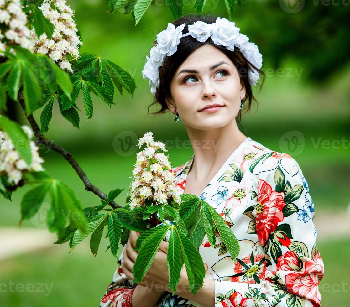 Frauenporträt mit einem Haar, das sich im Wind bewegt. porträt des jungen schönen russischen brünetten mädchens im sommergrünen park. Europäische weiße Frau im Kleid. foto