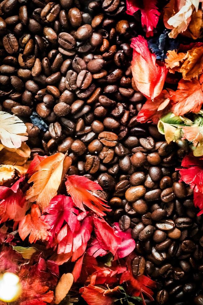 Das Hintergrundbild besteht aus Kaffeebohnen, die mit Blumen geschmückt sind. Hintergrundkonzept für Café foto
