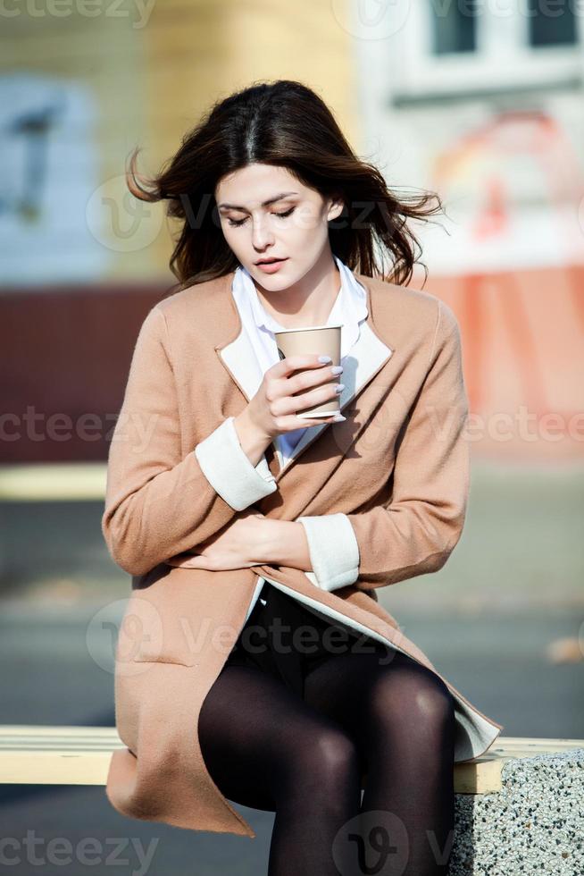 junge stilvolle Frau, die Tee in einer Stadtstraße trinkt. europäisches mädchen des hippies mit lattepapierglas. Wunderschöne junge Frau mit einer Tasse Kaffee in der Stadtstraße. Kaffeepause. Kaffee zum Mitnehmen. foto