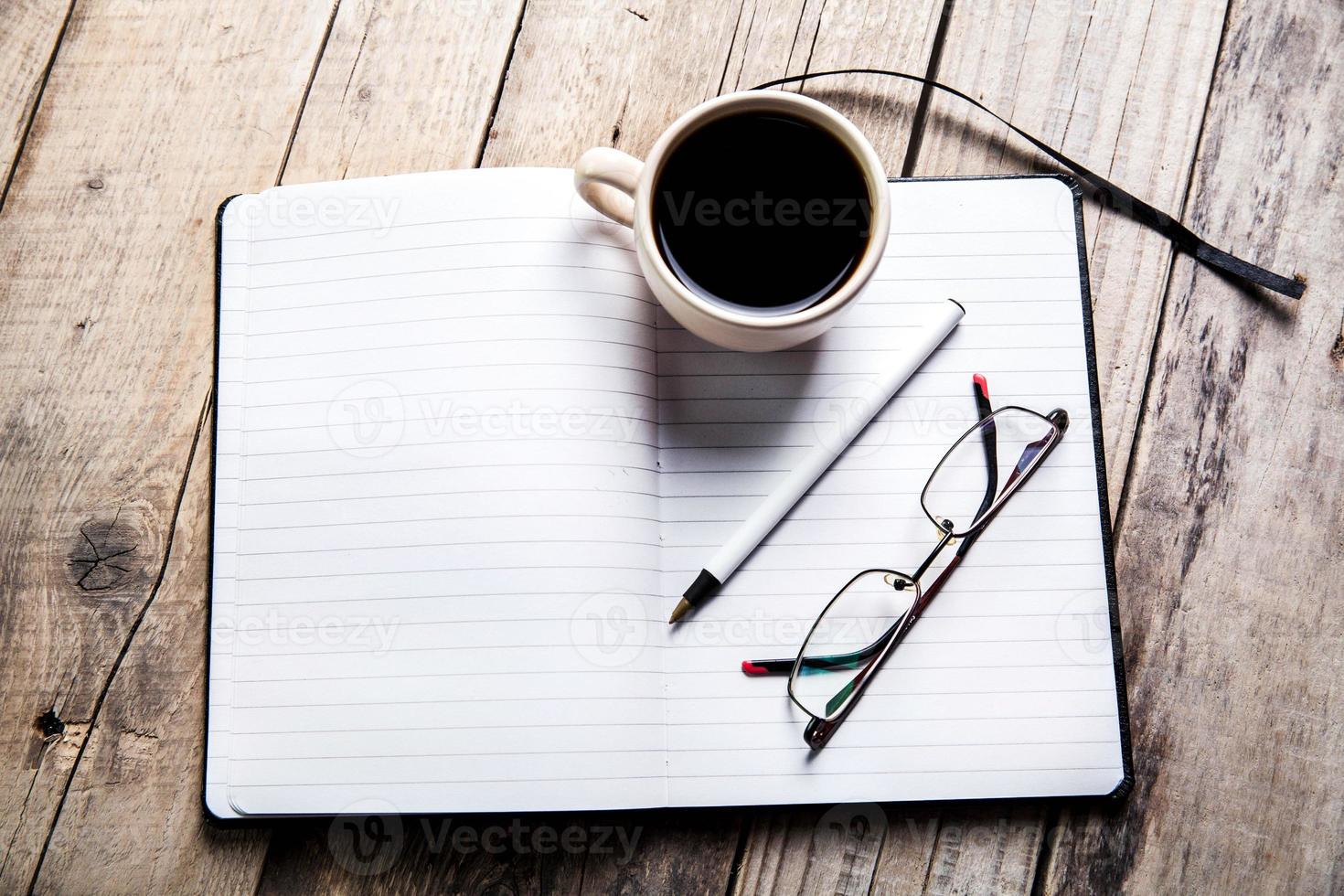 Gläser auf Notizbuch mit Stift und Tasse Kaffee foto