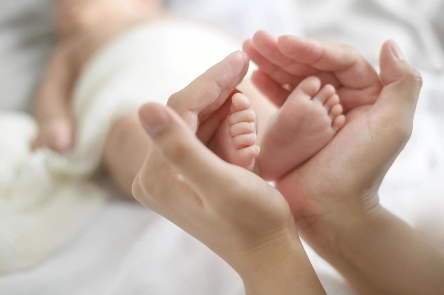 nah an der hand, die die füße des neugeborenen babys hält foto