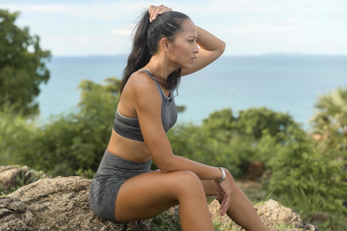 porträt einer schönen fitten frau in sportbekleidung auf einem berggipfel am meer, gesundheits- und reisekonzept. foto