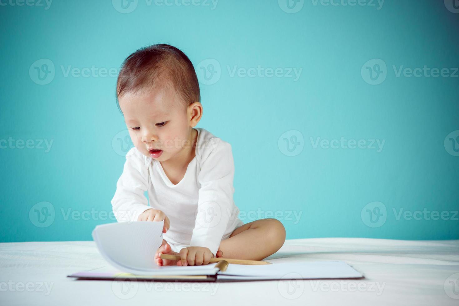 asiatisches Baby, das in einem Buch schreibt, gesundes Kind mit neuem Familienkonzept foto