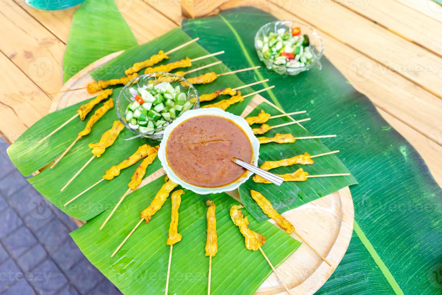 gegrilltes satay-schweinefleisch, thailand traditioneller beliebter lebensmittelstock mit holzstäbchen, fertig gekocht mit einer speziellen sauce daneben. foto