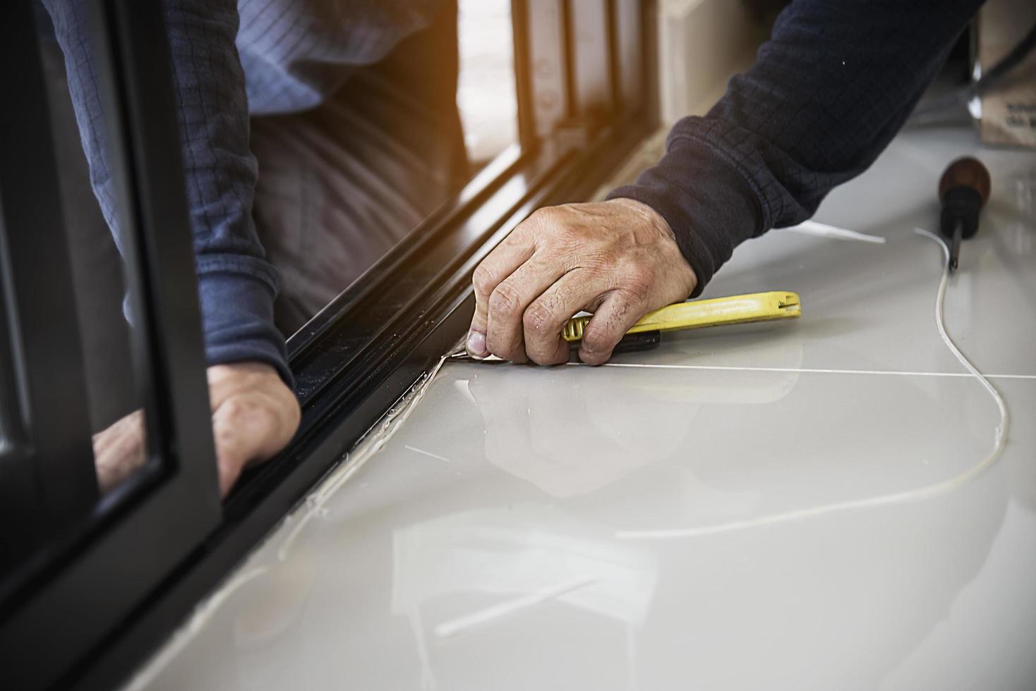 mann, der aluminiumrahmen mit gläsern und drahtgittertüren und fensterinstallationsarbeiten auf der baustelle durchführt foto