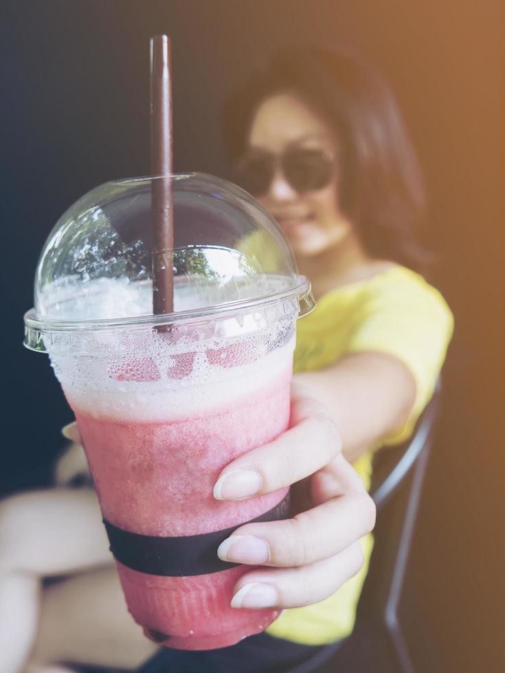 weinlesefoto der jungen asiatischen dame gibt tasse kalt gemischte erdbeere aus foto