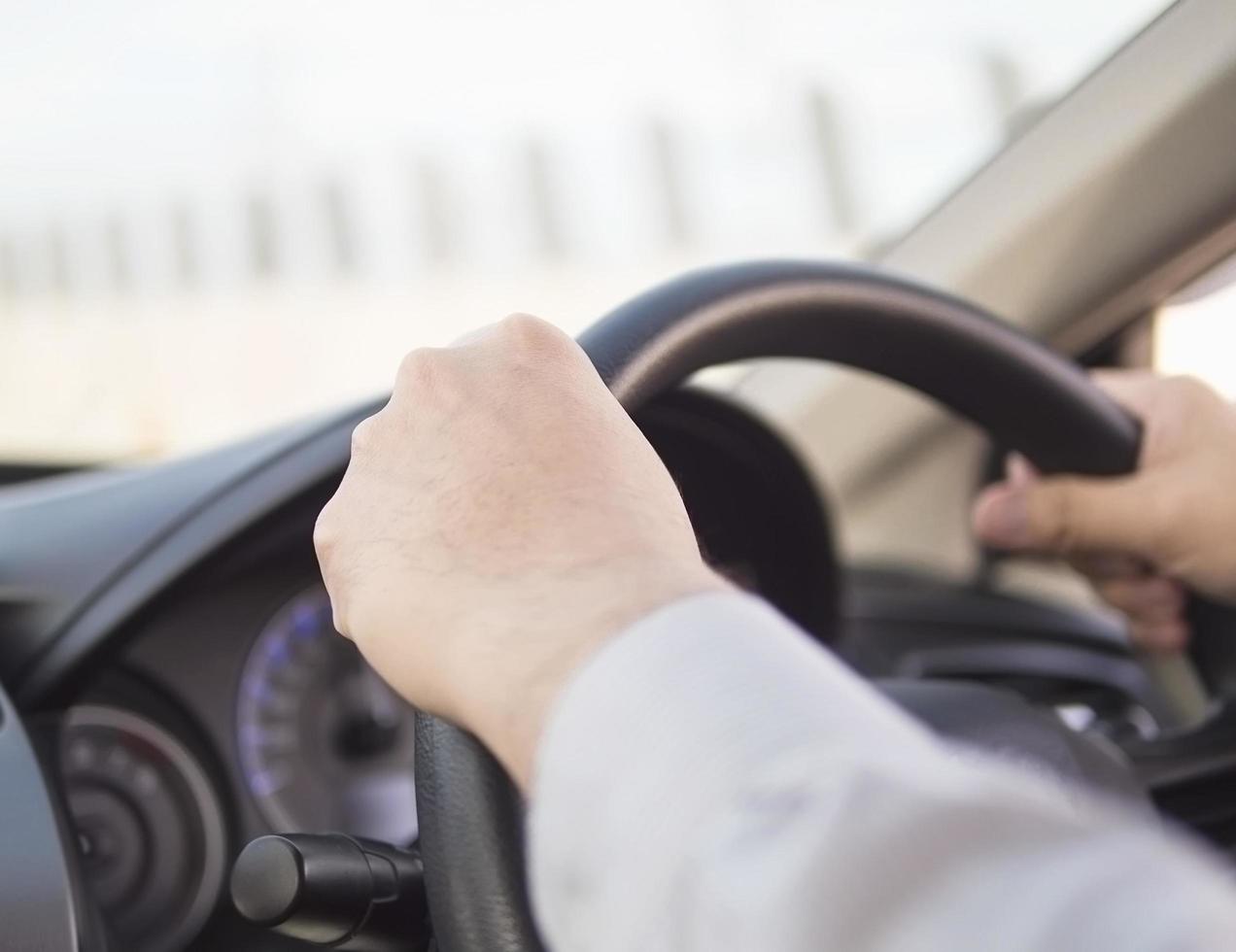 Nahaufnahme eines Mannes, der mit zwei Händen Auto fährt foto