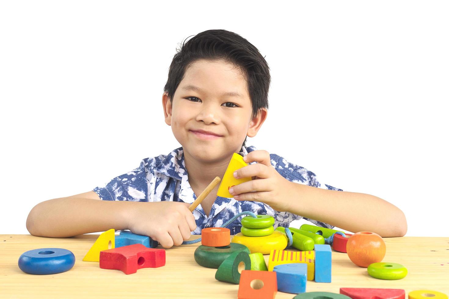 schöner asiatischer junge spielt buntes holzblockspielzeug foto