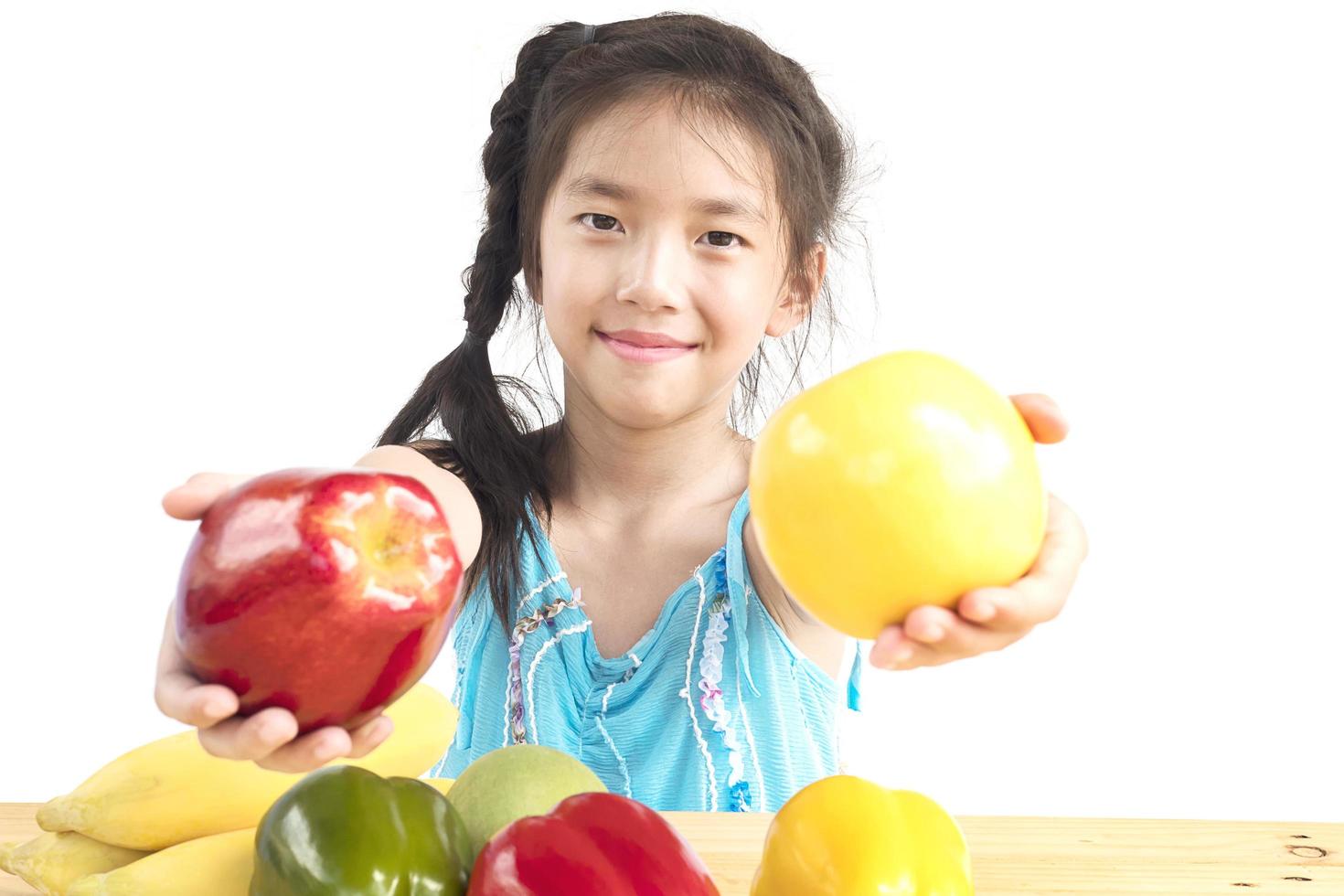 asiatisches gesundes Mädchen, das glücklichen Ausdruck mit buntem Obst und Gemüse der Vielfalt lokalisiert über weißem Hintergrund zeigt foto