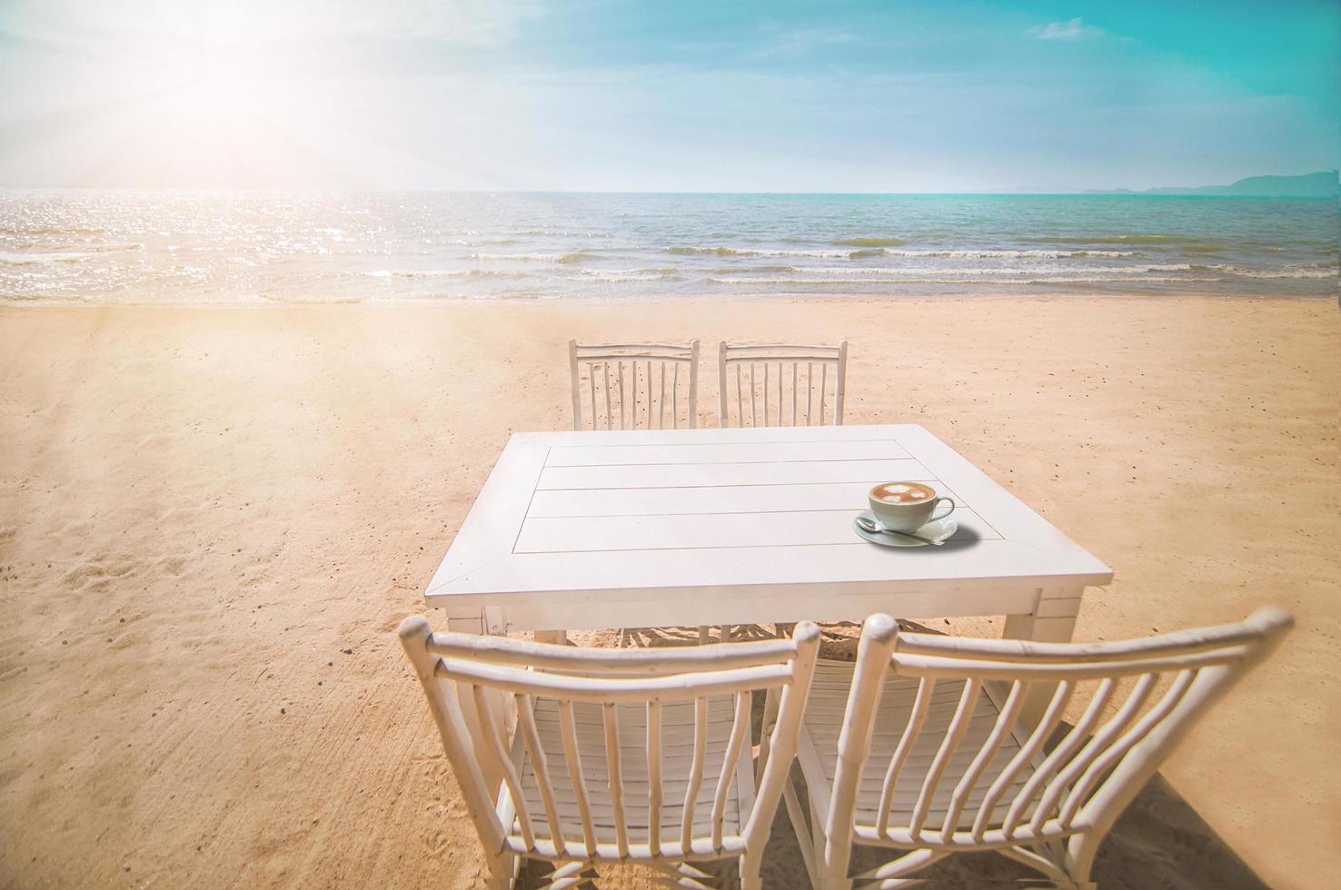 Weiße Reihe von entspannenden Stühlen und Tisch mit einer Kaffeetasse am Strand von Pataya, Thailand mit blauem Himmel und Sonnenlicht im Hintergrund foto