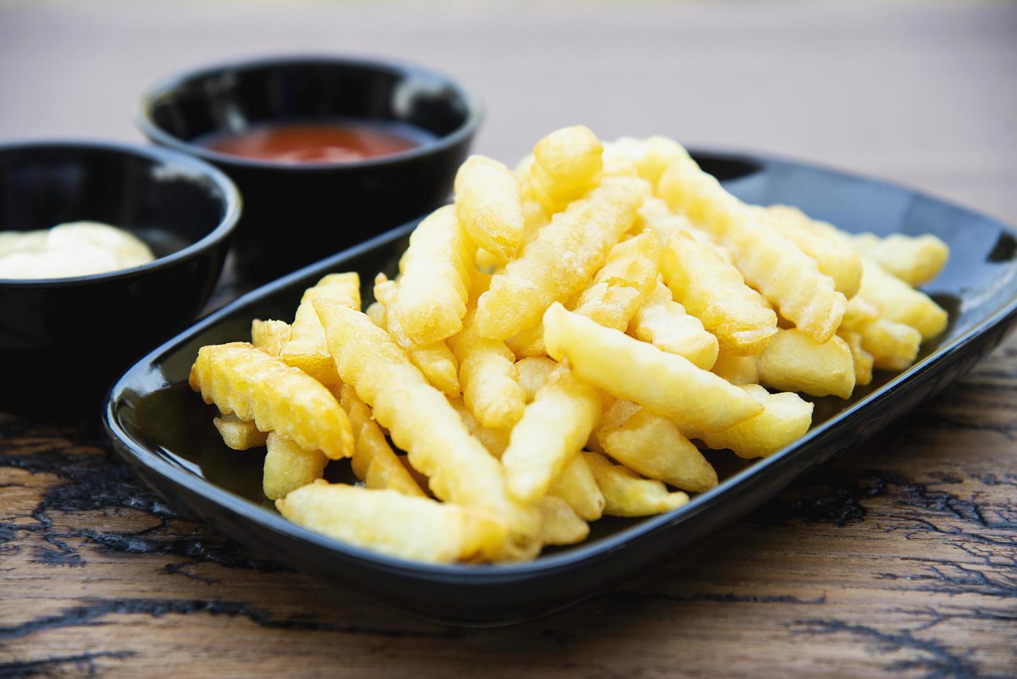 Seitenansicht von Pommes Frites mit Saucen auf Holzplatte foto