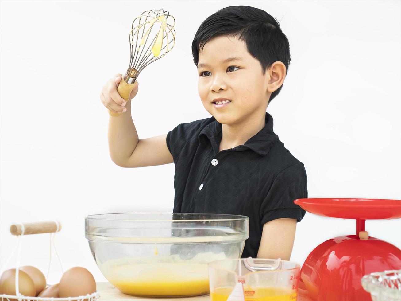 asiatischer Junge macht Kuchen auf weißem Hintergrund foto