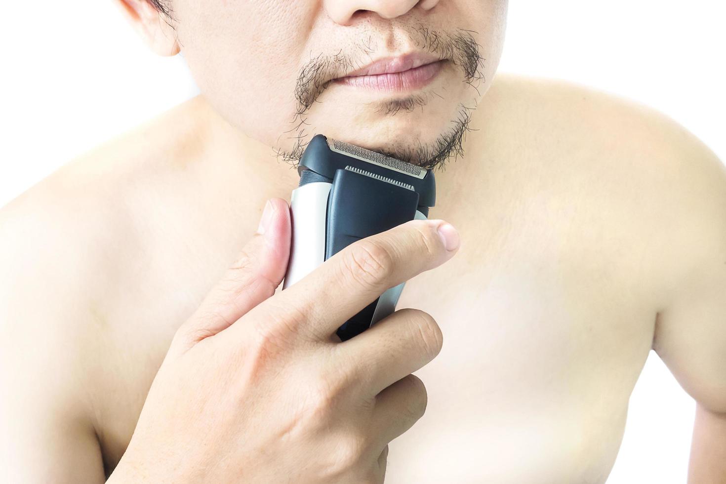Mann verwendet Rasierer gegenüber dem weißen Hintergrund isoliert foto