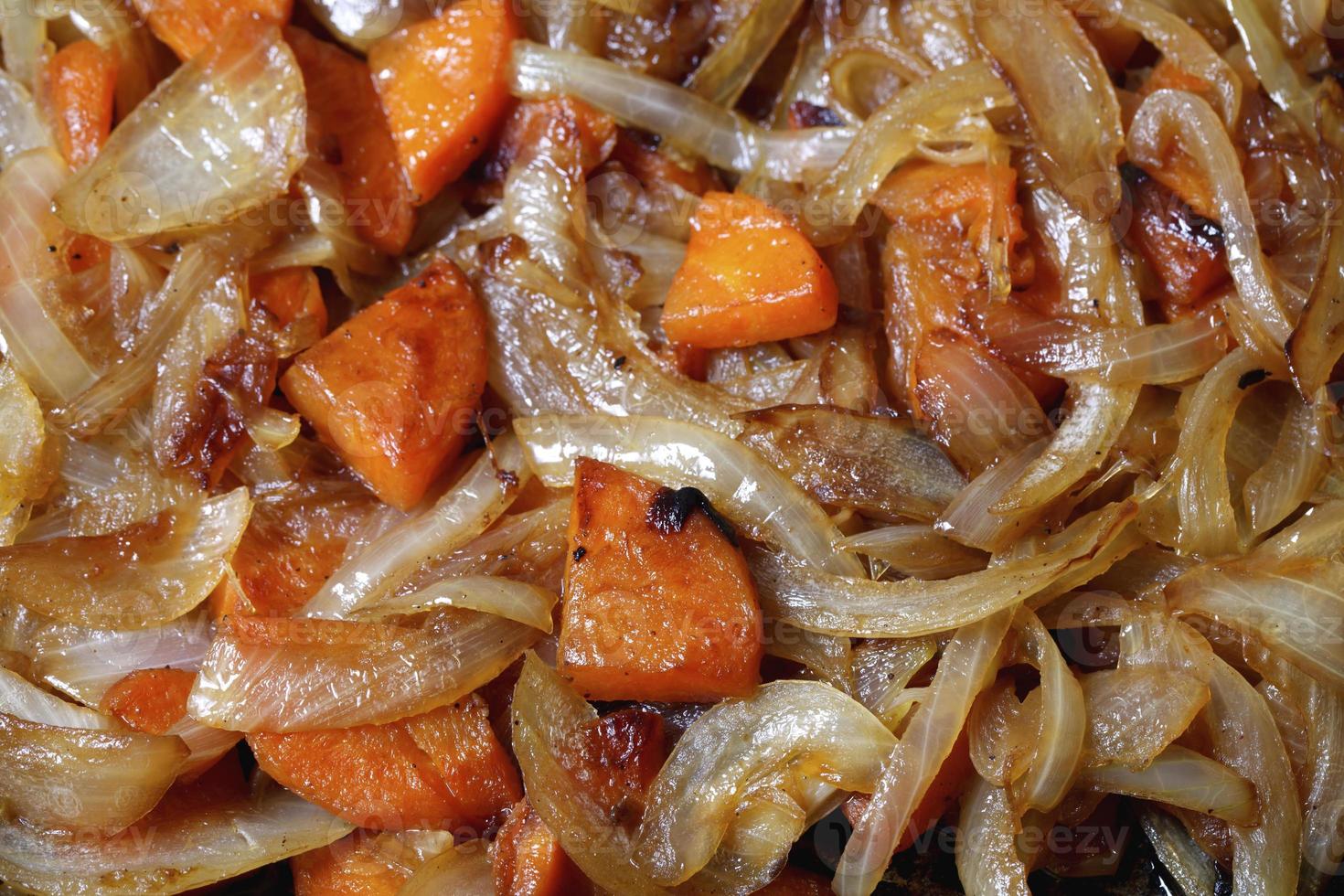 gebratene Zwiebeln und Karotten in der Pfanne, ein heller Hintergrund foto