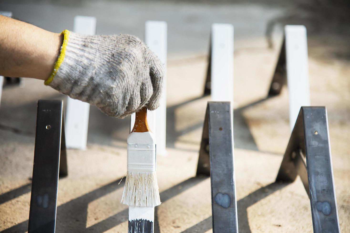 mann beschichtet weiße farbe für stahlmöbelteil - maler am arbeitskonzept foto