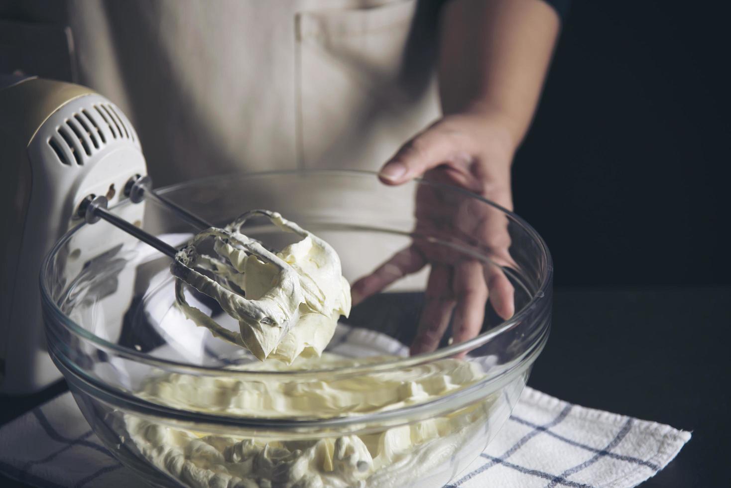 dame, die kuchencreme mit spachtel macht - hausgemachtes bäckereikochkonzept foto