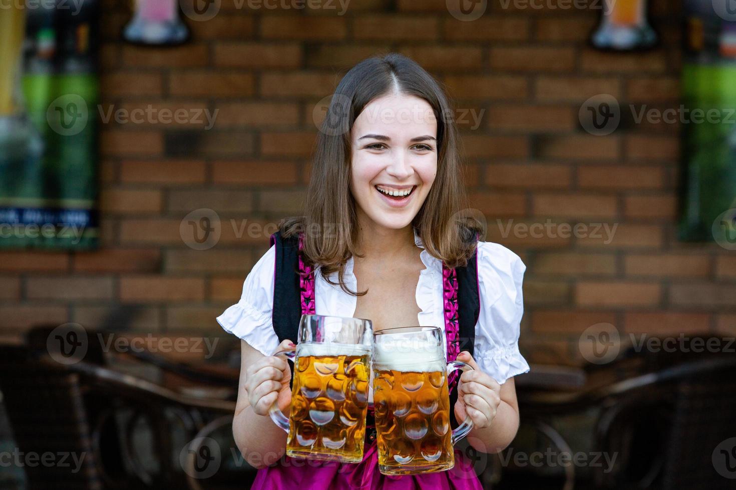 sexy russische frau im bayerischen kleid, das bierkrüge hält. foto