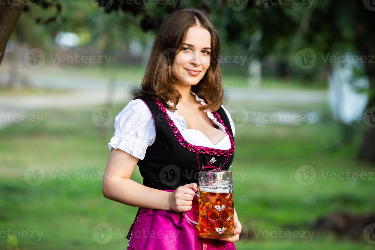 sexy russische frau im bayerischen kleid, das bierkrüge hält. foto