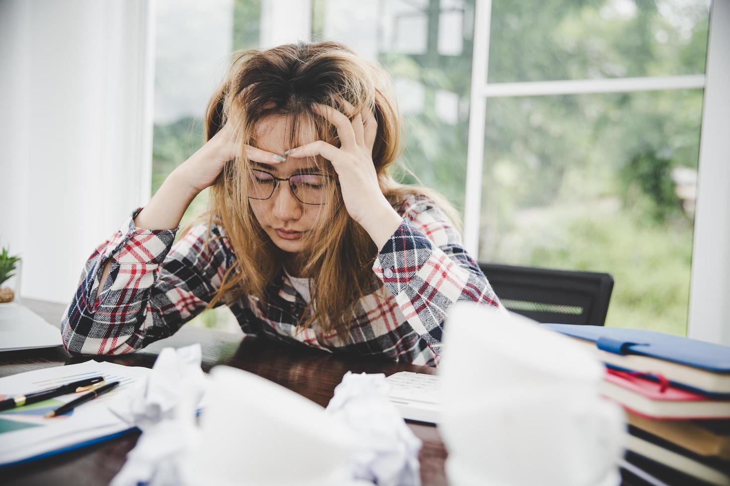 junge frustrierte frau, die im büro arbeitet foto